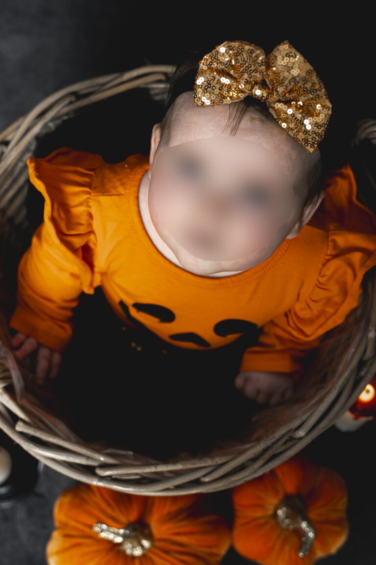 Bébé déguisé en citrouille dans un panier entouré de citrouille lors de son shooting halloween à mon home studio à Bordeaux