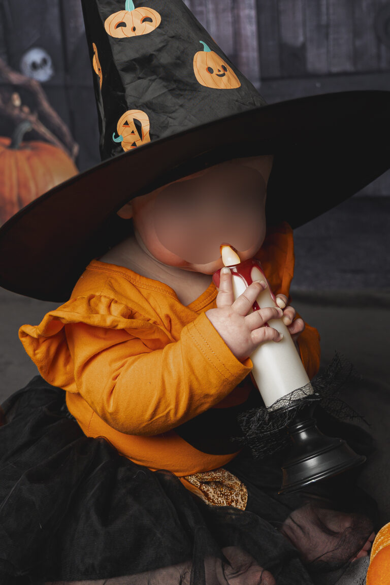 Bébé déguisé en citrouille avec un chapeau de sorcière qui tient une bougie lors de son shooting halloween au Home Studio à Bordeaux