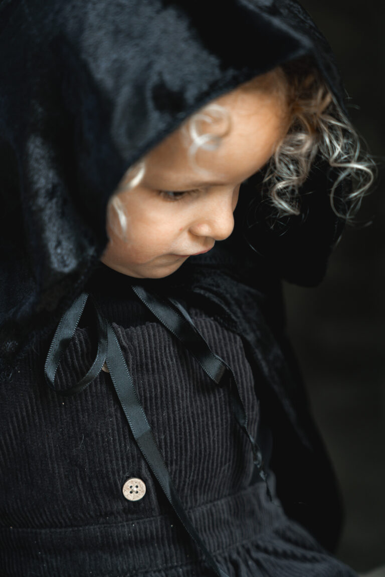 Portrait d'une petite fille qui porte une cape lors d'une séance photo halloween au parc majolan de blanquefort