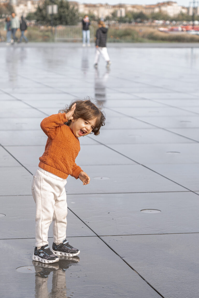 Jeune garçon qui sourit sur le miroir d'eau à Bordeaux lors d'une séance photo enfant