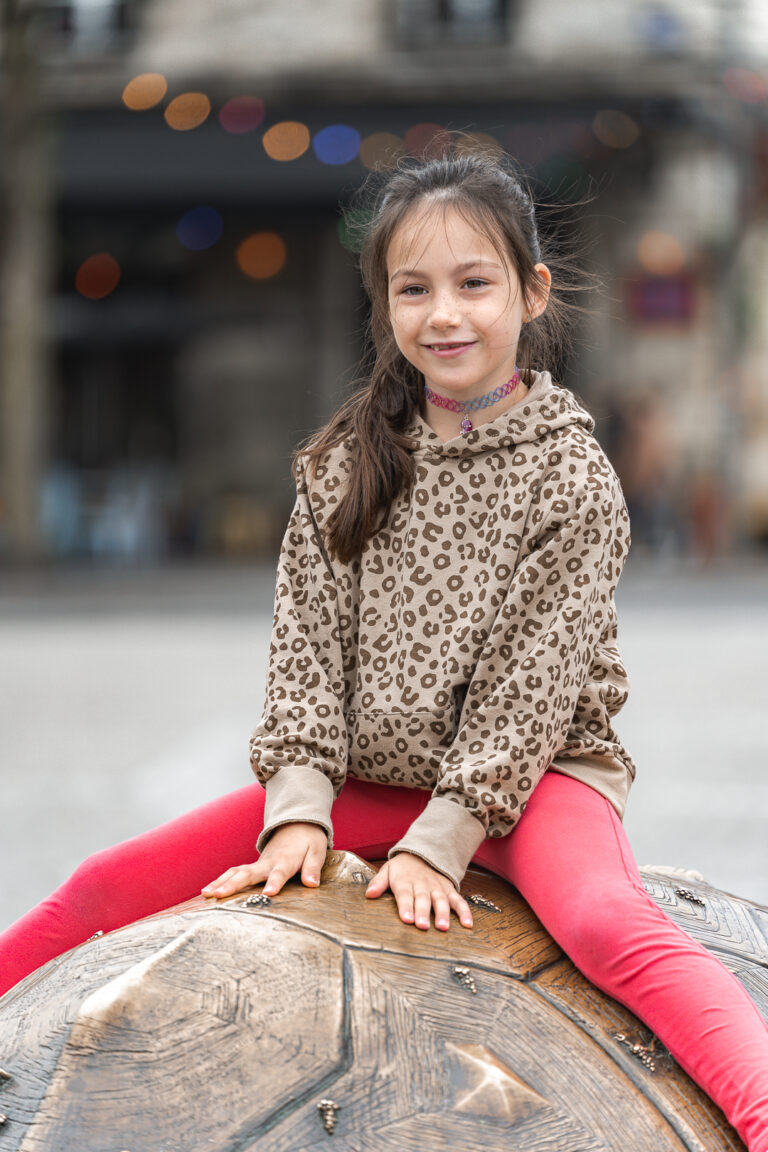 Jeune fille qui sourit sur la tortue de la place de la victoire à Bordeaux pendant une séance photo en famille