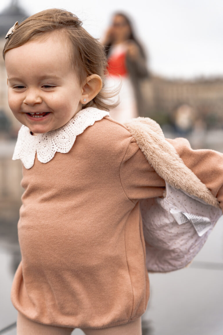 Petite fille qui court en riant sur le miroir d'eau de Bordeaux lors d'une séance photo enfant