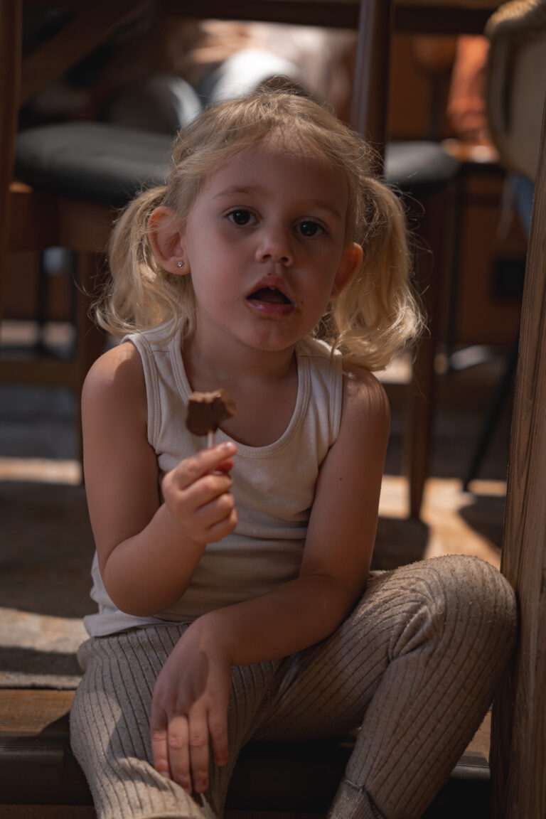 Portrait d'une petite fille qui mange une sucette au chocolat dans le restaurant ganache de Bordeaux lors d'une séance photo en famille