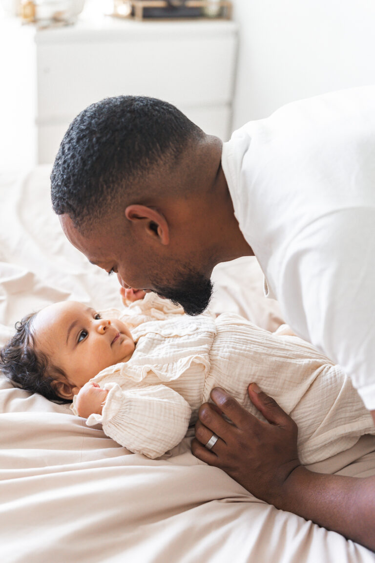 Papa qui sourit à sa fille allongée lors d'une séance photo fête des pères au home studio à Bordeaux
