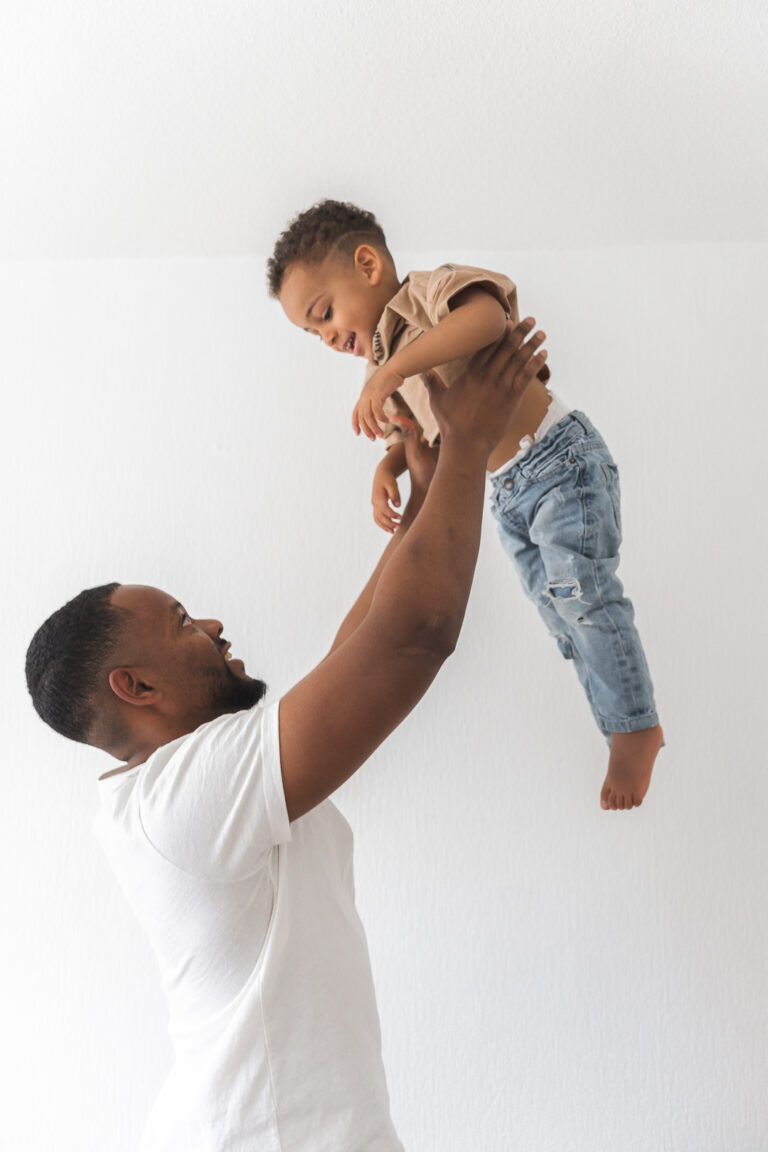 Papa qui lance son fils en l'air lors d'une séance photo fête des pères au home studio à Bordeaux