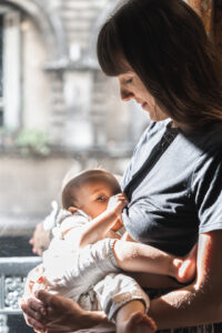 Maman qui allaite son bébé près de la fenêtre d'un café lors de son shooting allaitement en extérieur à Bordeaux