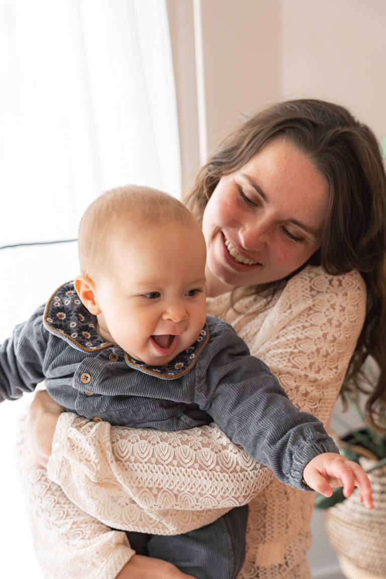 Maman qui tient son bébé en souriant lors d'une séance photo fête des mères au home studio à Bordeaux