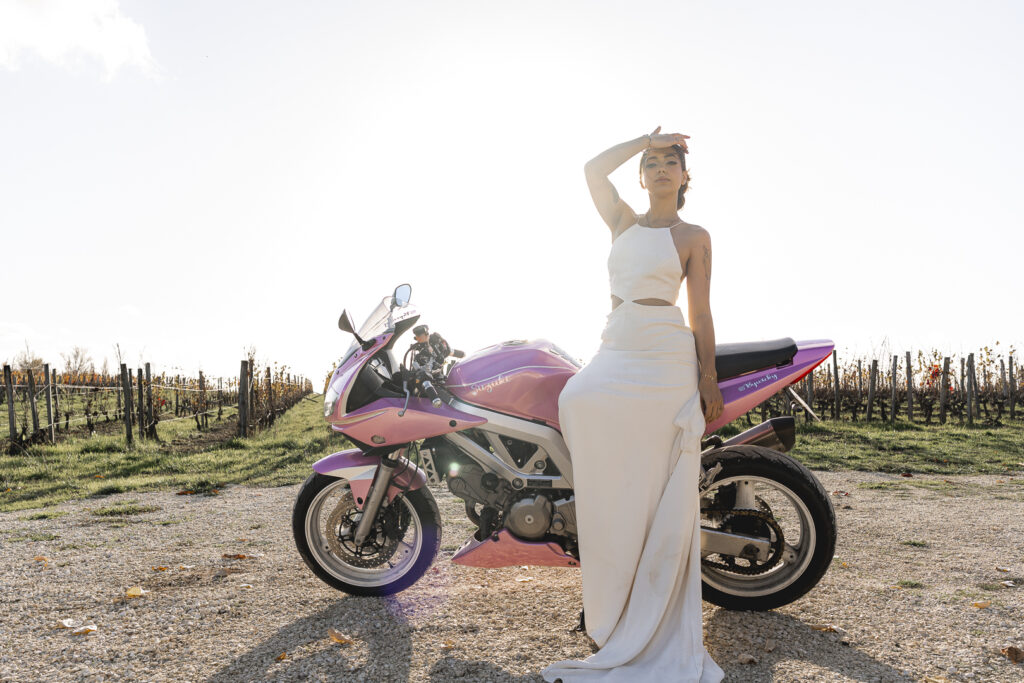 Mariée qui pose devant sa moto au coucher du soleil lors du portrait de la mariée de son mariage laïque au chateau du courlat à Lussac