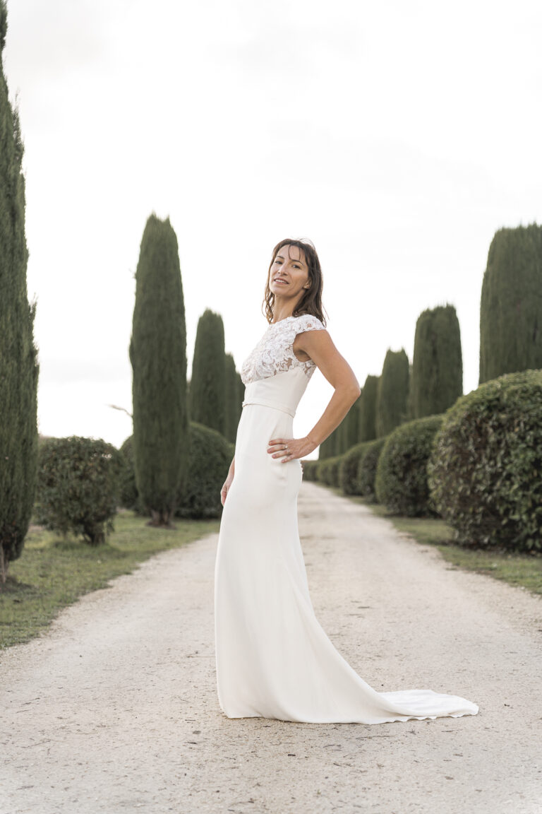 Mariée qui pose au milieu d'une allée bordée d'arbre lors du portrait de la mariée de la cérémonie laïque de son mariage au chateau de Courlat à Lussac