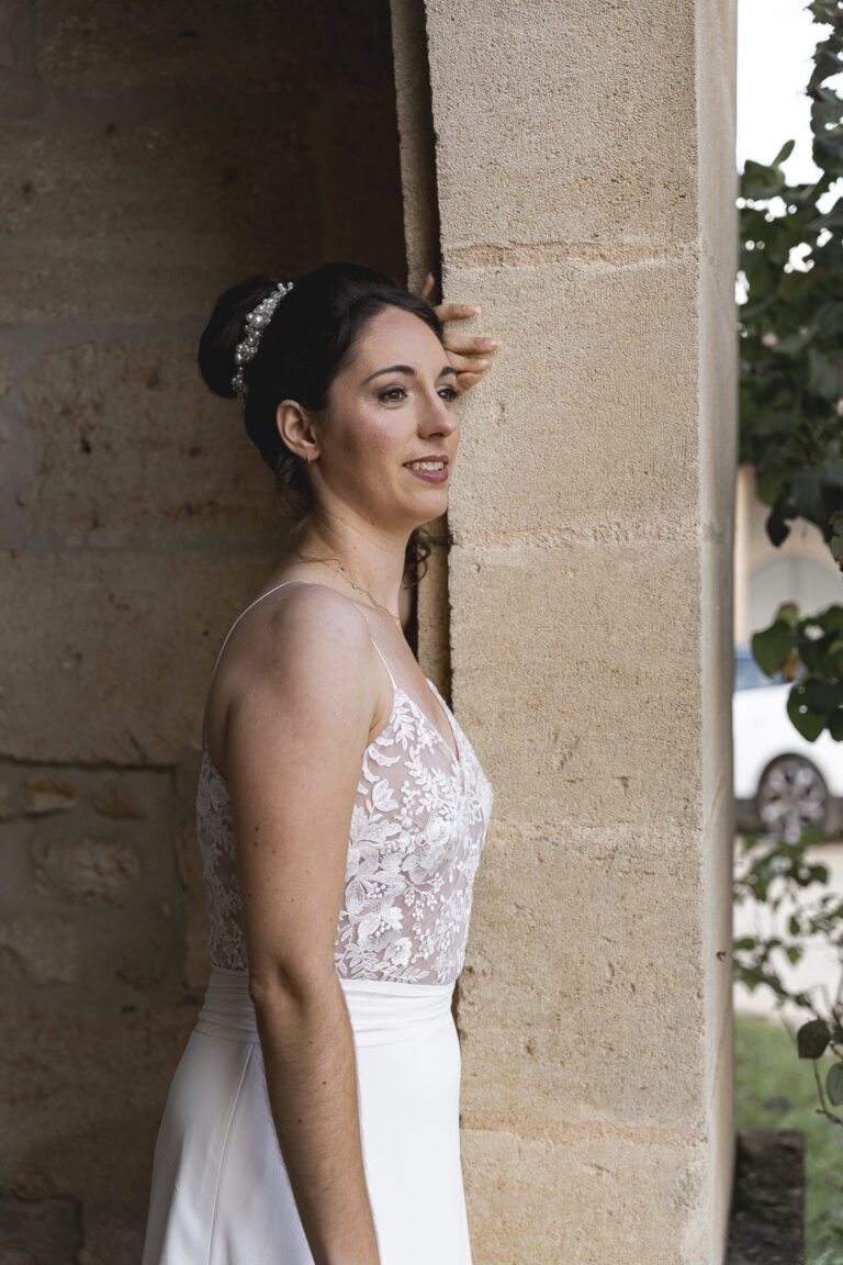Mariée accoudée à un mur, le regard au loin, lors du portrait de la mariée de la cérémonie laïque de son mariage au chateau de Courlat à Lussac