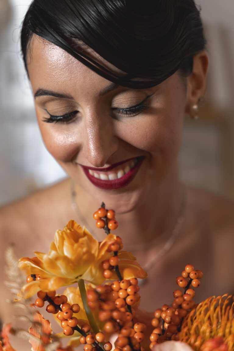 Portrait d'une mariée qui sourit à son bouquet lors du portrait de la mariée pendant la cérémonie laïque de son mariage au chateau de courlat à Lussac