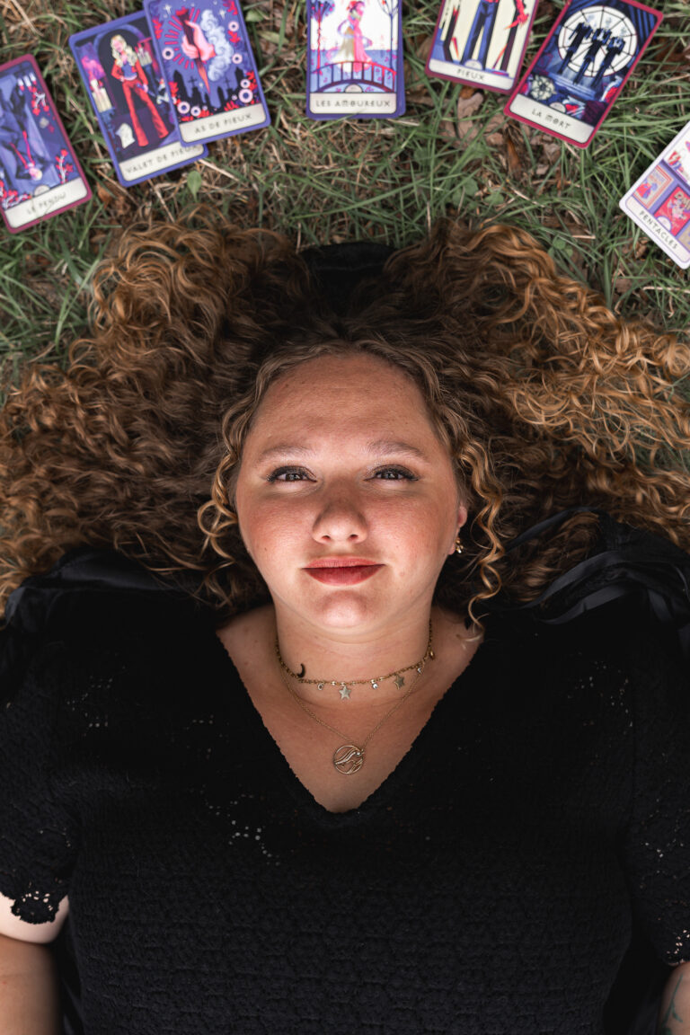 Femme allongée sur la pelouse entourée de cartes de tarots lors d'une séance photo halloween en extérieur au parc majolan de blanquefort