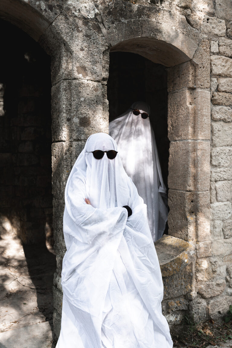 Fantôme adossé à un mur pendant qu'un autre l'observe de l'intérieur d'une chapelle pendant leur séance photo halloween en extérieur au parc majolan de Blanquefort