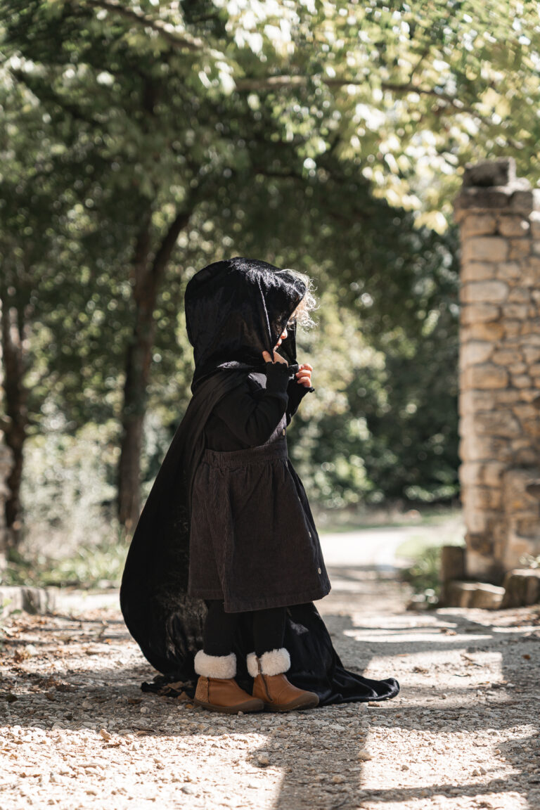 Enfant qui porte une cape sur un pont lors d'un shooting halloween en extérieur au parc majolan de blanquefort