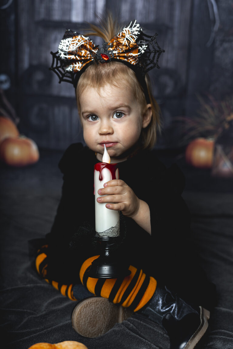 Enfant déguisée assise par terre qui souffle une bougie lors de son shooting Halloween au Home Studio à Bordeaux
