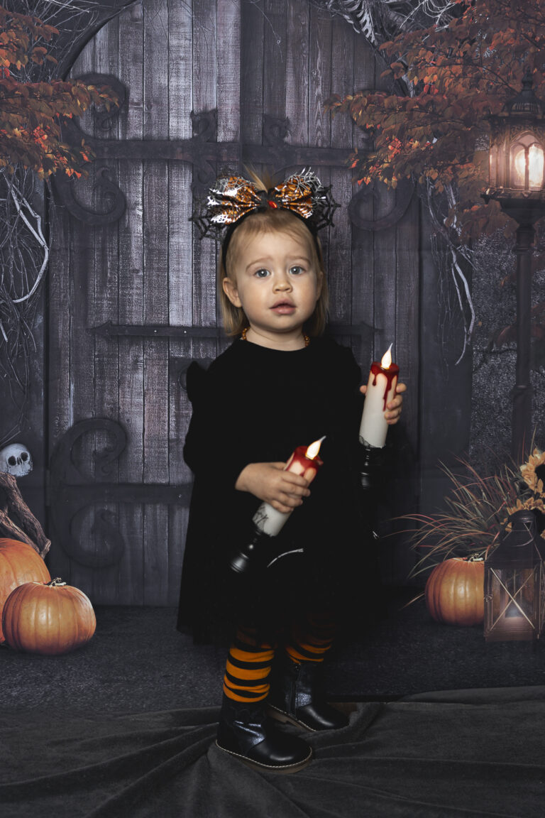 Enfant déguisée debout qui tient deux bougies lors de son shooting Halloween au Home Studio à Bordeaux