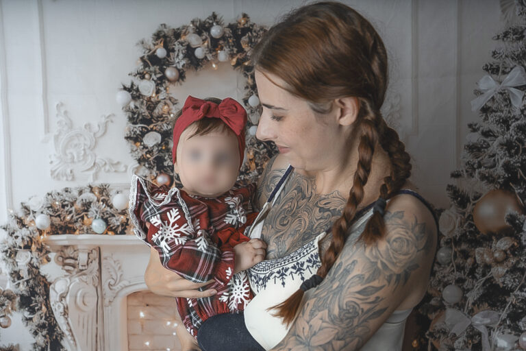 Portrait famille d'un bébé dans les bras de sa maman qui la regarde avec tendresse pendant un shooting photo de noël Bordeaux