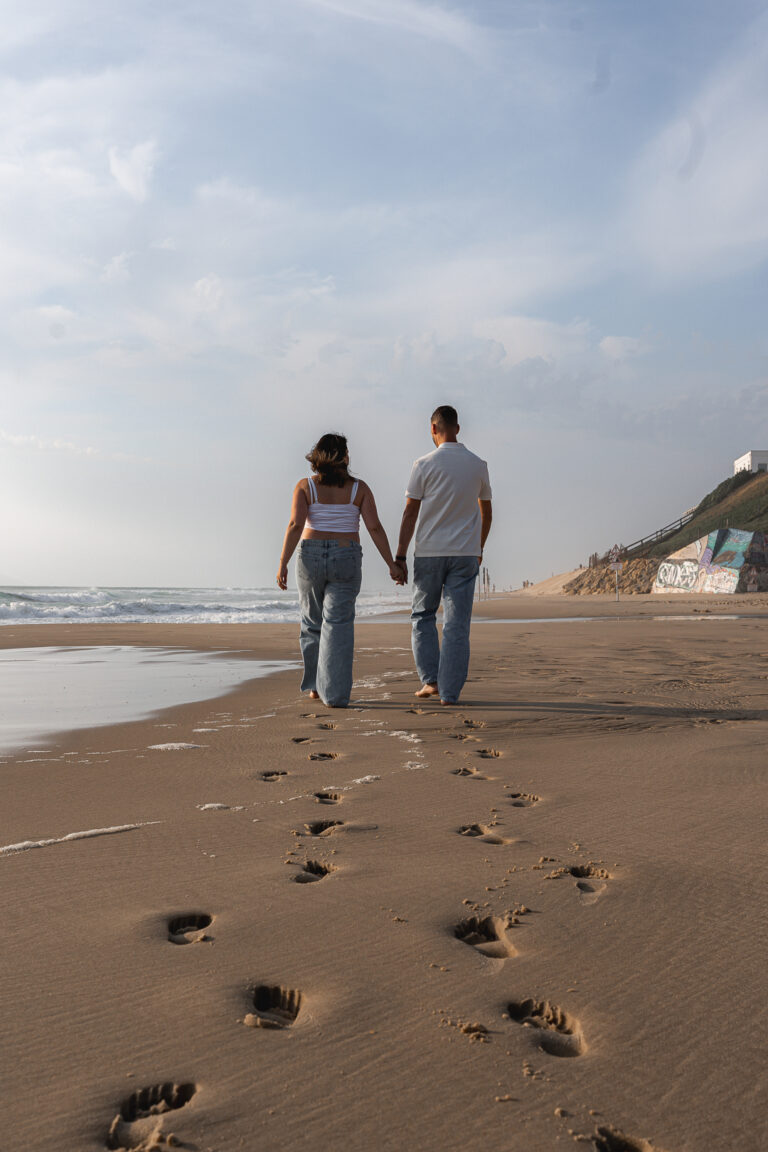 Couple qui marche main dans la main sur le sable au bord de la plage de Biscarosse sur le Bassin d'Arcachon lors de leur séance photo