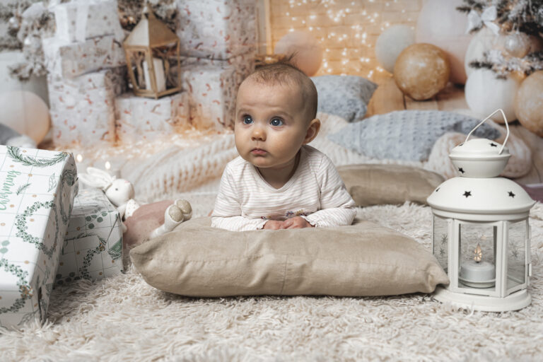 Bébé en tummy time sur un oreiller, qui regarde au loin, lors de sa séance photo noël au home studio à Bordeaux