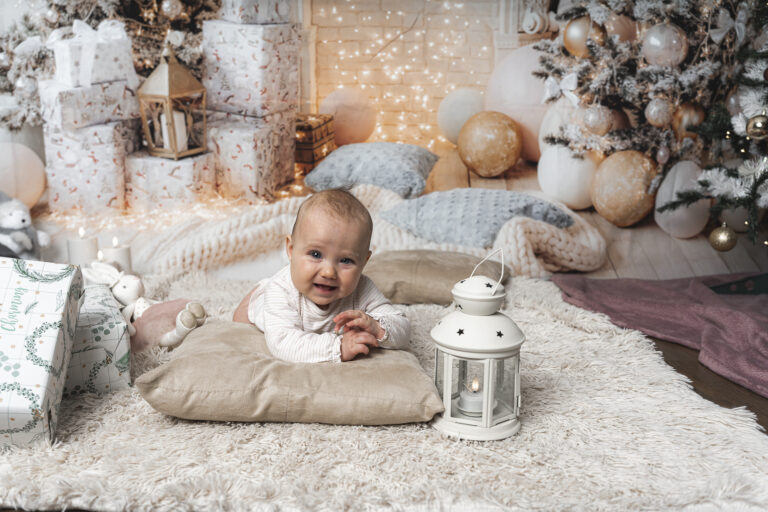 Bébé qui rigole, positionné en tummy time sur un oreiller lors de sa séance photo noël à mon home studio à Bordeaux