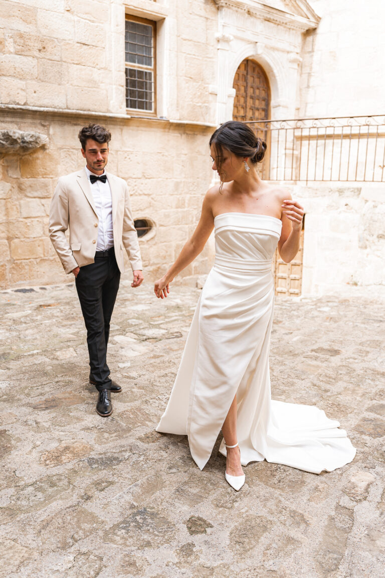 Mariés qui marchent dans la cour d'un château libournais pendant la séance couple de leur mariage religieux à saint-émilion