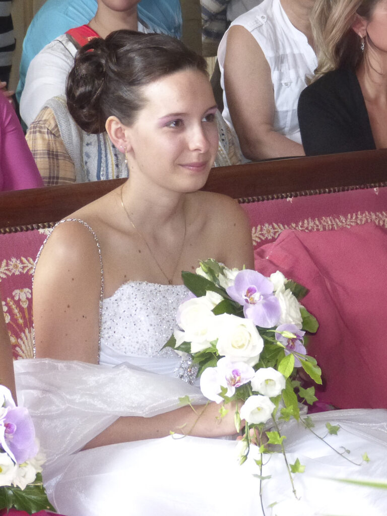 Photographe assise sur un fauteuil en robe de mariée et tenant un bouquet de fleurs dans la mairie de Châteaudun