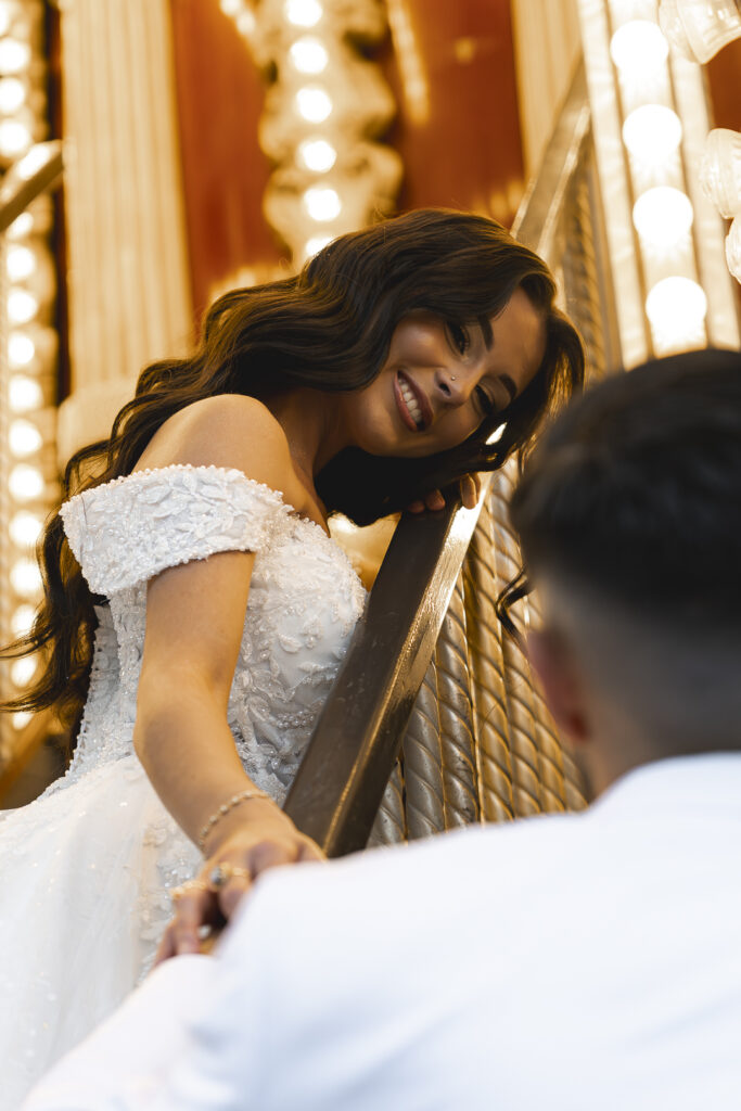Mariée qui admire son époux appuyée contre une rambarde du carrousel lors de la séance couple de leur mariage civil à bordeaux