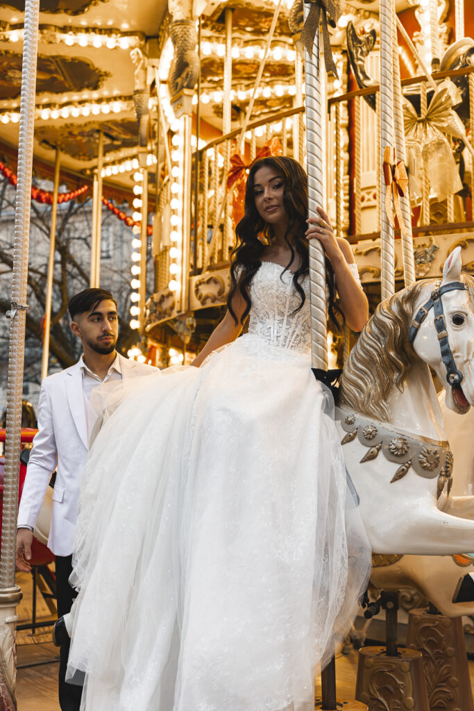 Marié qui admire sa femme sur un cheval du carrousel de l'avenue tourny lors de la séance photo couple de leur mariage à Bordeaux