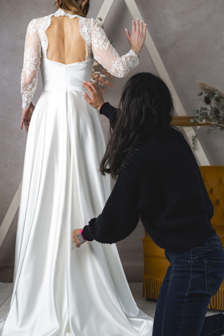 Mise en situation d'une créatrice de robe de mariée qui retouche une robe lors d'une séance photo corporate en immersion à St Sulpice de Cameyrac