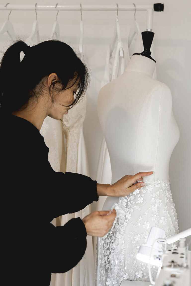 Mise en situation d'une créatrice de robe de mariée qui retouche une robe lors d'une séance photo corporate en immersion à St Sulpice de Cameyrac