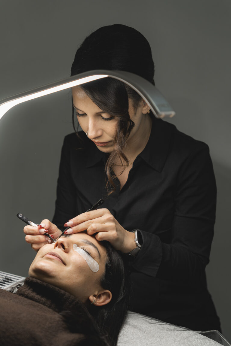 Lash artist qui pose des extensions de cils à une cliente lors de sa séance photo corporate en immersion dans son salon à bordeaux