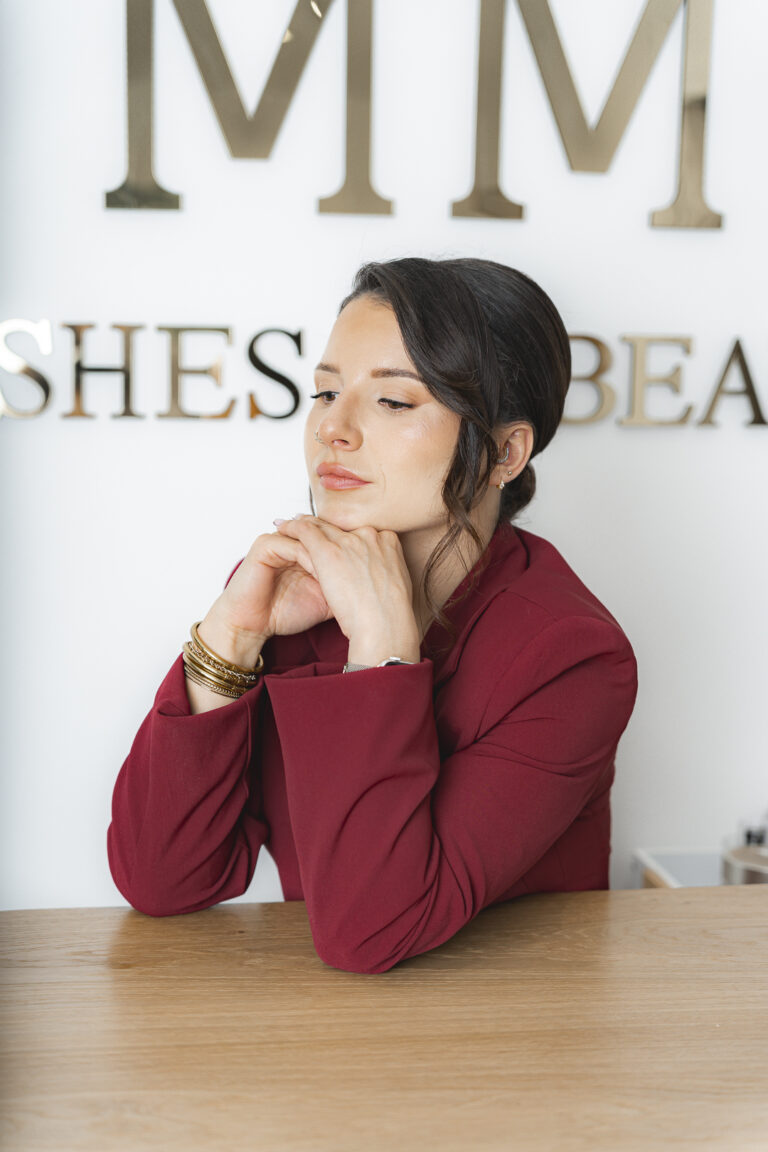Lash Artist tête posée sur les mains et coude sur son bureau, devant le nom de son entreprise lors de sa séance photo corporate en immersion dans son salon à bordeaux